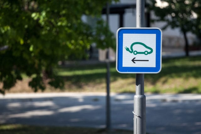 Selective blur on a road sign indicating an electric car charging station used to fill with electricity electrical vehicles, abiding by European laws on traffic signalization.