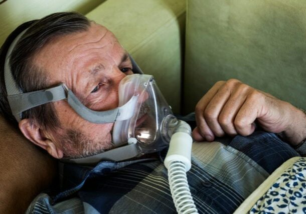 An elderly man with the COVID-19 coronavirus in an oxygen mask uses artificial ventilation