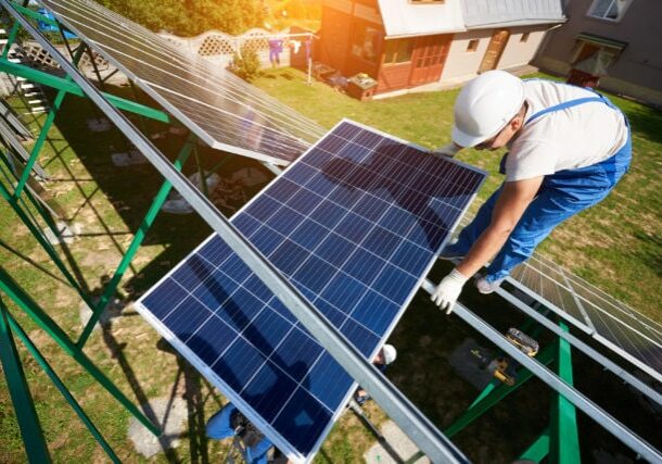 Mounter installing solar panels on green carcass. Innovative solution for electricity saving, using renewable energy of sun. High-tech exterior, modern equipment, ecological friendly, green energy.